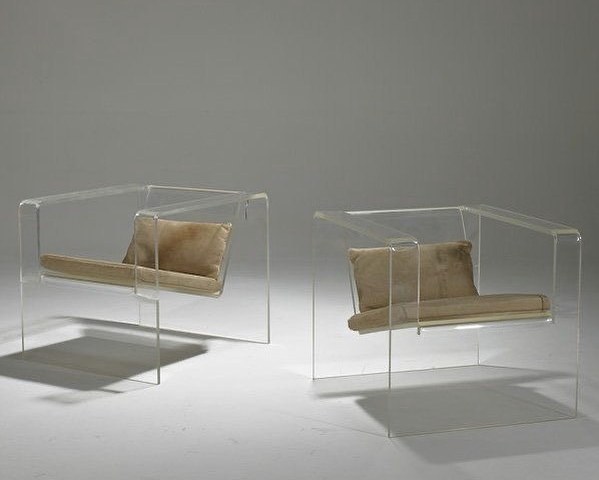 Two acrylic lounge chairs in a pale grey room