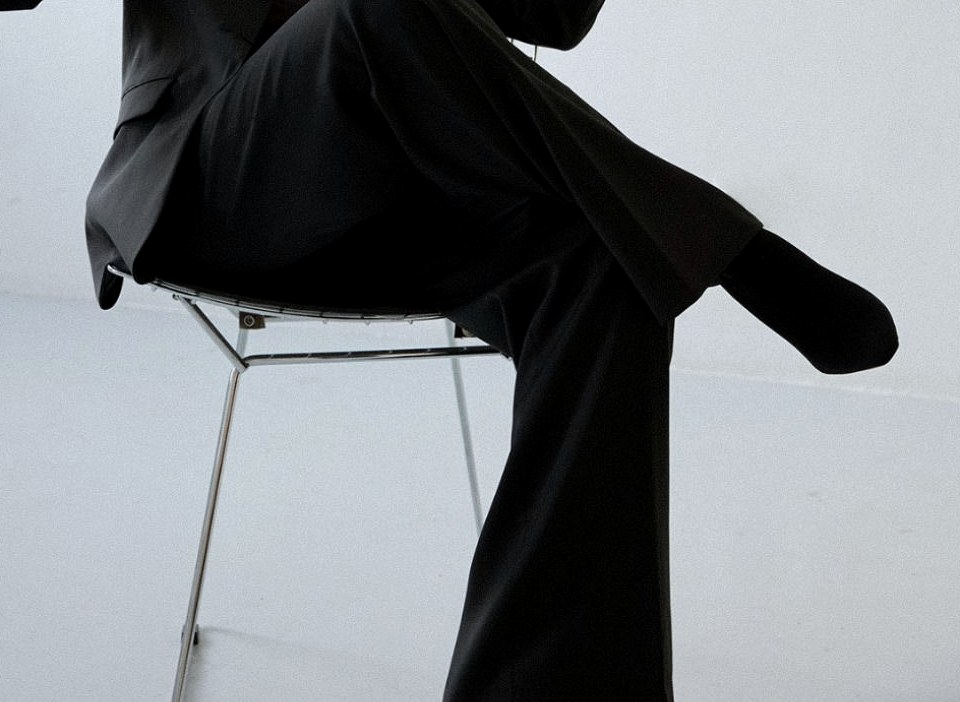 A cropped black skirt and legs beside a chrome office chair