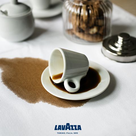 Tipped espresso cup on a white tablecloth